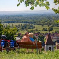 Couple de cyclotouristes profitent d'une pause détente sur un banc surplombant un vignoble de la Forêt-Noire du Sud