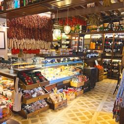 Intérieur d'une épicerie fine à Palma avec charcuteries suspendues, vitrine à fromages, étagères à vin et sol carrelé.