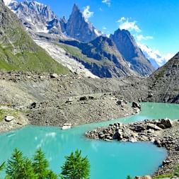 Magnifique lac de montagne turquoise entouré de terrain rocheux dans les Alpes françaises près du Mont Blanc, avec des sommets enneigés.