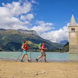 Randonneuse longeant le lac de Resia et son célèbre clocher immergé