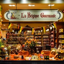 Vitrine de l'épicerie fine La Belgique Gourmande avec chocolats et produits exposés, décorée de drapeaux belges.