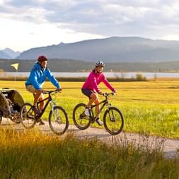Un couple de cyclotouriste avec leur enfant dans une remorque vélo