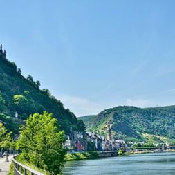 Le Château de Cochem perché sur une colline boisée surplombant la vallée de la Moselle avec la ville de Cochem en bas.