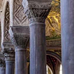 Intérieur de la Basilique de Porec montrant des colonnes en pierre sculptées avec des chapiteaux décoratifs et des mosaïques byzantines dorées.