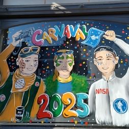 Fresque de carnaval colorée à Bailleul montrant trois personnages costumés avec maquillage, confettis et texte '2025' sur fond bleu foncé.