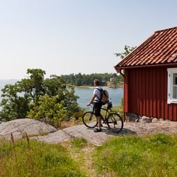 Cycliste devant une maison en bois et un paysage suédois