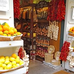 Épicerie fine traditionnelle majorquine Intérieur d'une épicerie fine majorquine avec oranges et citrons frais dans des paniers en osier, guirlandes de paprika rouge et étagères en bois.