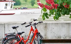 Deux vélo garé contre un muret avec un bateau de croisière fluvial en arrière-plan