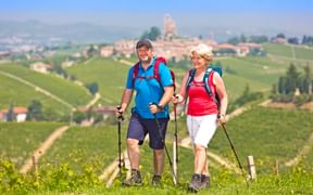 Couple de randonneurs dans le Piémont, avec en arrière plan, le village médiéval de Serralunga d'Alba
