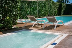 Zone piscine de l'hôtel Palazzo del Garda avec jacuzzi bouillonnant au premier plan, deux chaises longues sous parasol sur terrasse en bois.