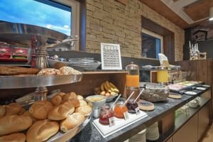 Buffet petit-déjeuner à l'Hôtel Ertl avec petits pains frais, distributeurs de jus, confitures, céréales et divers articles.