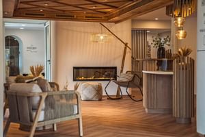 Réception d'hôtel moderne au Bergrose Strobl avec comptoir en bois, coin salon contemporain, cheminée et éclairage chaleureux.