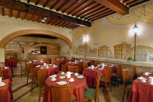 Intérieur de restaurant italien traditionnel avec poutres apparentes, arche en brique et tables dressées avec nappes rouges et vaisselle blanche.