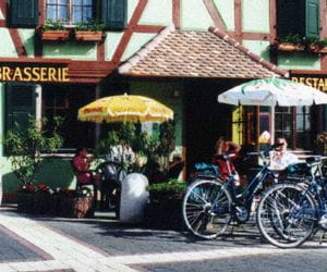 photo datant du début des années 2000 montrant des vélos garés devant une maison alsacienne à colombage accueillant un restaurant typique. 