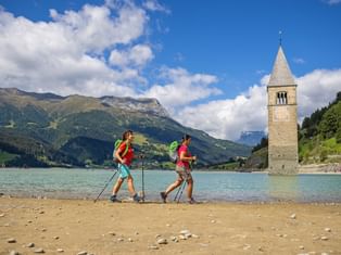 Randonneuse longeant le lac de Resia et son célèbre clocher immergé