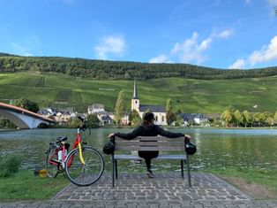 La Moselle à vélo, cyclotouriste se reposant sur un banc sur les rives de la Moselle
