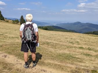Randonneur admirant la vue sur la plaine d'Alsace depuis les chaumes, au dessus de Munster
