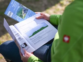 Randonneuse étudiant un topoguide et une carte IGN