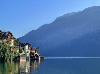Village historique de Hallstatt avec maisons colorées se reflétant dans les eaux calmes du lac, entouré de montagnes escarpées.