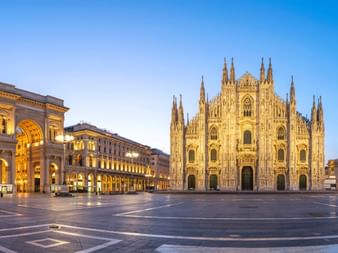 Cathédrale de Milan et Galleria Vittorio Emanuele II sur la Piazza del Duomo au crépuscule. La cathédrale gothique avec ses flèches ornées domine la place vide.