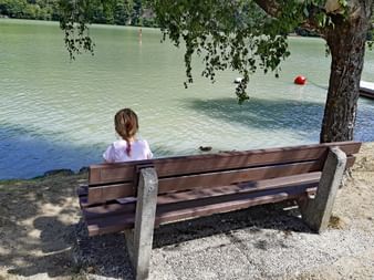 Une jeune enfant assise sur un banc devant le Danube