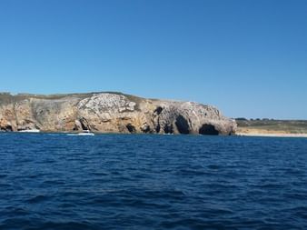 Falaises rocheuses avec grottes le long du littoral de Morgat sur la presqu'île de Crozon, vues depuis la mer bleue sous un ciel dégagé.