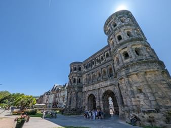 L'ancienne porte romaine Porta Nigra à Trèves avec son architecture distinctive en grès sombre, ses multiples ouvertures voûtées et sa tour cylindrique.