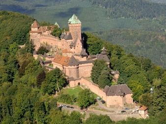 Vue aérienne château du Haut-Koenigsbourg Vue aérienne du château du Haut-Koenigsbourg, forteresse médiévale aux murs de grès rouge et tours, entourée de forêt dense.