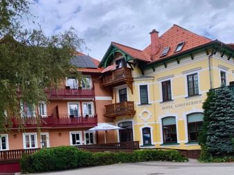 Hôtel autrichien traditionnel Goisererhof à Bad Goisern avec façade jaune, toits de tuiles rouges, balcons en bois et volets verts.