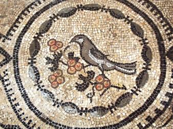 Mosaïque romaine antique d'Aquilée représentant une colombe tenant une branche fleurie, entourée de bordures circulaires décoratives beiges et noires.