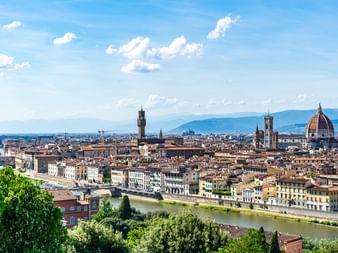 Vue panoramique de Florence avec l'Arno traversant la ville. Le dôme de la cathédrale et la tour du Palazzo Vecchio dominent l'horizon.