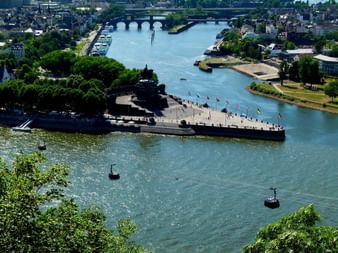 Vue aérienne du Deutsches Eck à Coblence montrant la confluence de deux rivières, avec un monument sur une péninsule triangulaire et téléphériques.