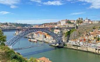 Pont Dom Luis I enjambant le Douro à Porto Vue panoramique du pont Dom Luis I de Porto, pont en arc de fer à deux niveaux traversant le Douro avec bâtiments colorés sur les collines.