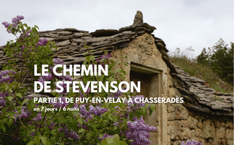 Ancienne maison en pierre avec toit en ardoise et fleurs de lilas violettes sur le Chemin de Stevenson de Puy-en-Velay à Chasseradès.