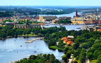 Vue panoramique de Stockholm montrant les voies navigables, îles vertes, bâtiments historiques et tour de l'hôtel de ville. Bateaux sur l'eau bleue.