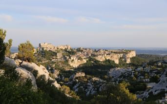 Vue panoramique du village des Baux-de-Provence perché sur des falaises calcaires avec des bâtiments en pierre anciens et des ruines.