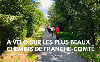 Groupe de cyclistes sur un chemin asphalté à travers une forêt verdoyante en Franche-Comté. La lumière du soleil filtre à travers les arbres.