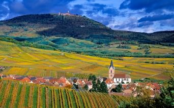 Vue d'un village alsacien niché au bas d'une colline surmontée du Haut-Koenigsbourg