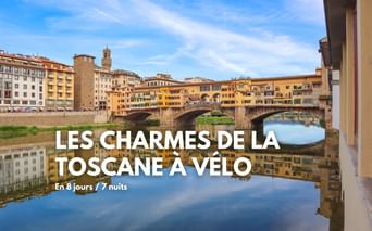 Pont Ponte Vecchio avec bâtiments historiques enjambant l'Arno à Florence. Bâtiments jaunes et oranges se reflétant dans l'eau calme sous ciel bleu.