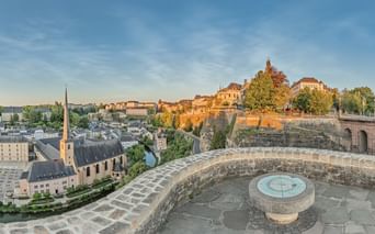 Plateforme circulaire en pierre du Monument du Millénaire avec rose des vents, vue sur la vieille ville de Luxembourg avec clocher et fortifications.
