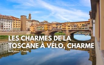 Pont Ponte Vecchio avec bâtiments historiques enjambant l'Arno à Florence, Toscane. Façades colorées se reflétant dans l'eau calme sous ciel bleu.