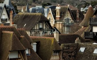 Vue aérienne des toits d'architecture normande traditionnelle à Deauville avec tuiles d'argile, maisons à colombages et cheminées.