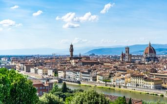 Vue panoramique de Florence avec l'Arno traversant la ville. Le dôme de la cathédrale et la tour du Palazzo Vecchio dominent l'horizon.