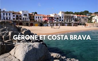 Plage de sable avec côte rocheuse et maisons méditerranéennes colorées sur la Costa Brava, Espagne. Eau turquoise claire et ciel bleu.