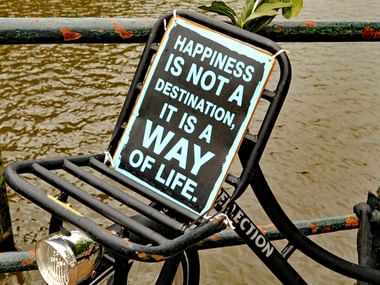 Vélo attaché près d'un quai et portant une pancarte "Happiness is not a destination, it is a way of life."