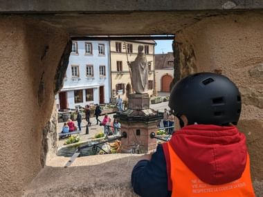Petit cycliste observant la place principale d'Eguisheim