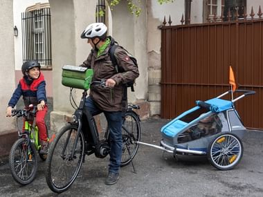 Un père et son fils à vélo, avec une petite fille en remorque, dans les rues de Strasbourg