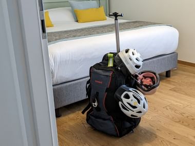 Valise étiquetée et casques à vélo dans une chambre d'hôtel