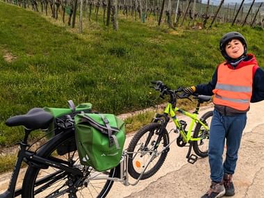 Garçon posant avec son vélo suiveur dans les vignes alsaciennes
