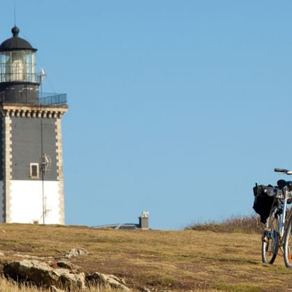Vélo de randonnée garé devant le phare de Pen Men sur l'île de Groix en Bretagne